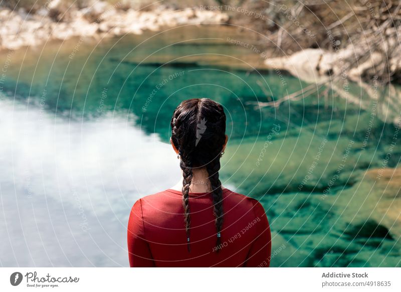 Back view woman with braids looking at the river forest back view vacation lifestyle anonymous nature travel young stones outdoor people leisure activity