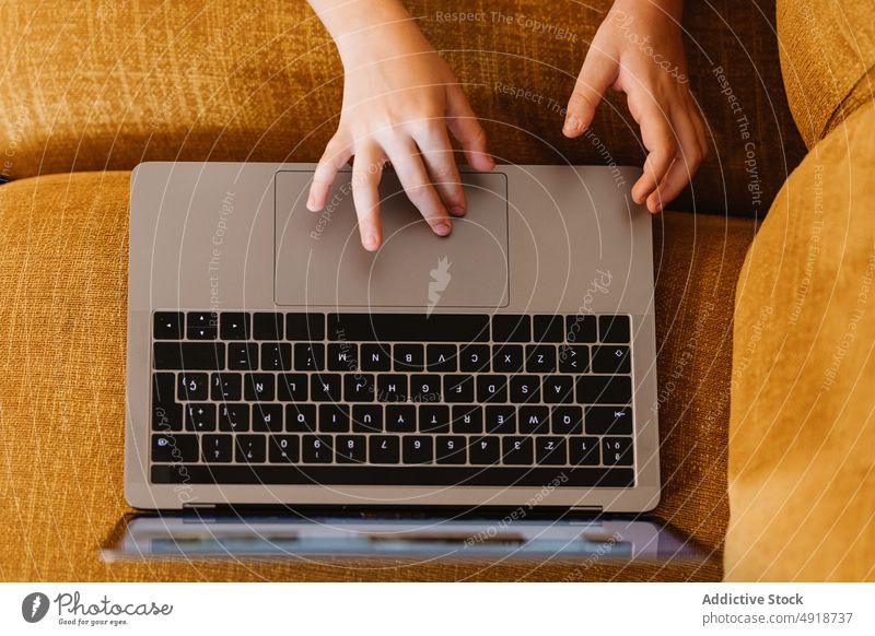 Anonymous boy lying on a sofa using the laptop child computer caucasian technology male kid indoors home childhood little game internet play young digital