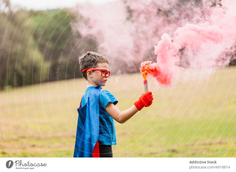 Little superhero with smoke bomb boy park costume play power focus lawn colorful bright child imagination fantasy adorable summer vibrant inspiration season