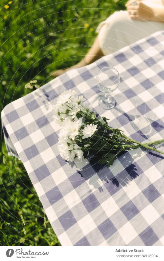 Unrecognizable woman sitting on table with flowers field countryside bouquet nature pastime recreation feminine summer female lady rural flora grassy leisure