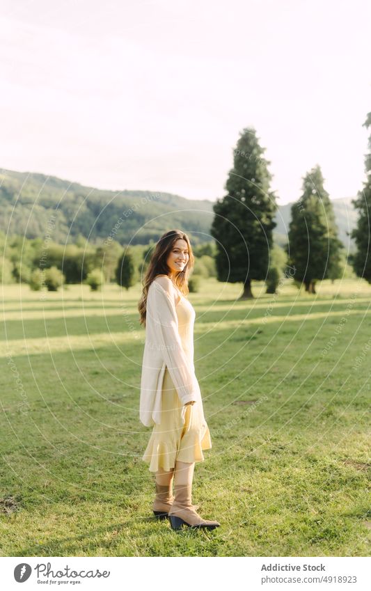 Young smiling woman standing in field in summer countryside delight meadow grass dress glad nature pastime cheerful smile feminine woodland female rural flora