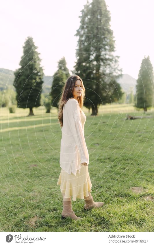 Young woman standing in field in summer countryside meadow grass dress nature pastime recreation feminine woodland female lady rural flora grassy leisure