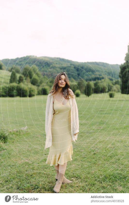 Young woman standing in field in summer countryside meadow grass dress nature pastime recreation feminine woodland female lady rural flora grassy leisure