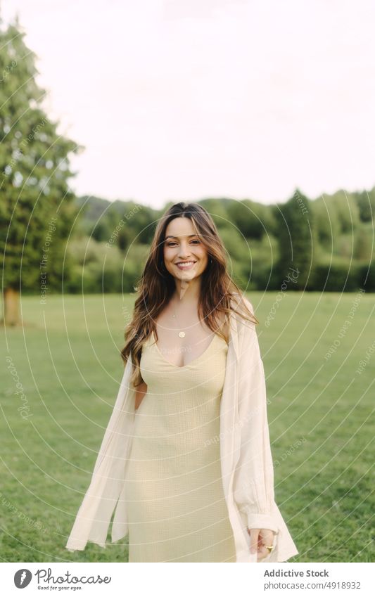 Young smiling woman standing in field in summer countryside delight meadow grass dress glad nature pastime cheerful smile feminine woodland female rural flora