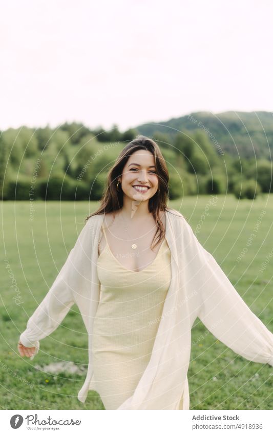 Young smiling woman standing in field in summer countryside delight meadow grass dress glad nature pastime cheerful smile feminine woodland female rural flora