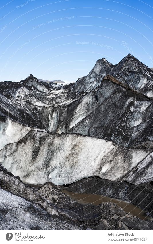 Massive glacier covered with ash in volcanic mountainous terrain landscape picturesque scenery nature winter formation ice scenic geology iceland rough blue sky