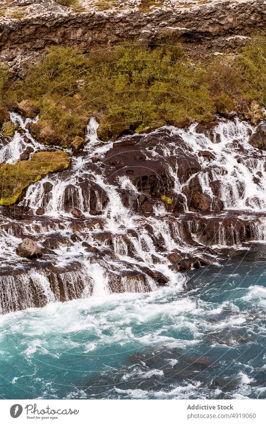 Waterfall streaming through cliff out of lava field waterfall river nature landscape volcanic breathtaking cascade rocky picturesque flow riverside hraunfossar