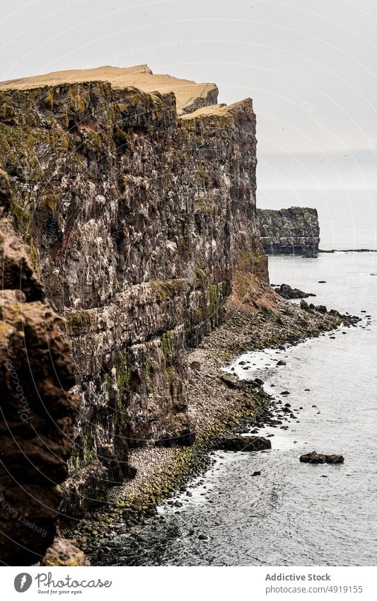 Cliff edge near rippling sea cliff shore coast mountain seaside gloomy massive water nature ridge cloudless iceland seawater steep wild landscape uneven terrain