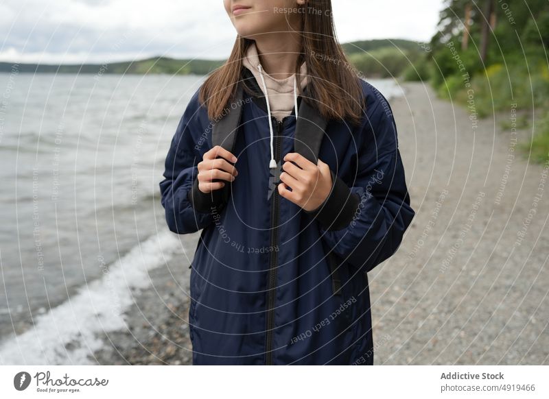 Unrecognizable girl standing on the sea shore dressed in winter clothes lake cold water nature beach landscape beautiful travel outdoor blue view tourism coast