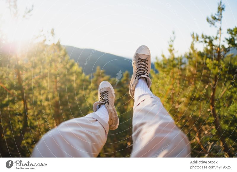 Unrecognizable traveler sitting in nature leg forest recreation woods leisure chill journey sunbeam tourist pastime explore foliage verdant person adventure