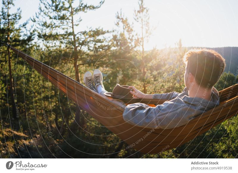 Man resting in hammock in nature man forest relax recreation woods leisure chill pastime headwear tree hat male summer plant sunshine journey summertime trendy