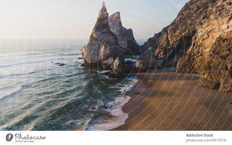 Rocky cliff near rippling sea mountain rock beach water shore nature coast tropical summer sand resort seashore ocean cloudless seaside scenery seacoast