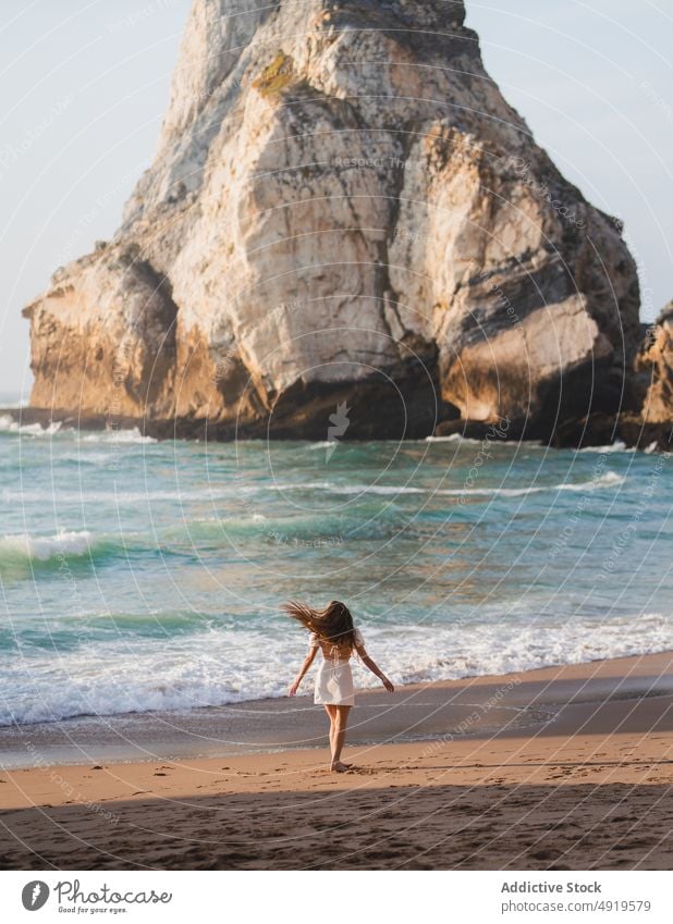 Woman walking on shore with cliffs woman traveler sea rock beach water sunset journey sunlight sundown tourist evening pastime leisure adventure active female