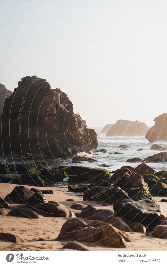 Coast with boulders near sea cliff rock beach water shore nature coast stone tropical summer sand resort seashore steep ocean sunlight cloudless sky uneven