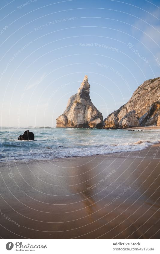 Rocky cliffs near waving sea rock beach water shore nature coast coastal wave tropical wild splash tide foam summer sunlight sand resort seashore ocean seaside