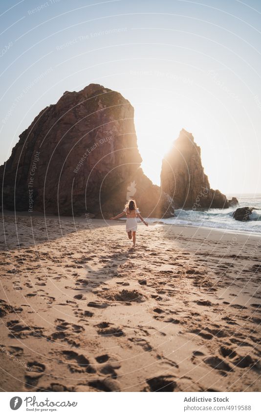 Woman running on shore with cliffs woman traveler sea rock beach water sunset journey sunlight sundown tourist evening pastime leisure adventure active female