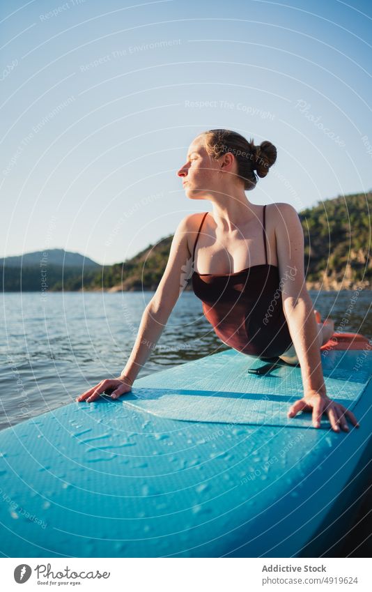 Woman lying on paddleboard in lake woman leisure hobby water rest nature wellbeing swimwear summer sup board slender shore float relax forest vacation coast