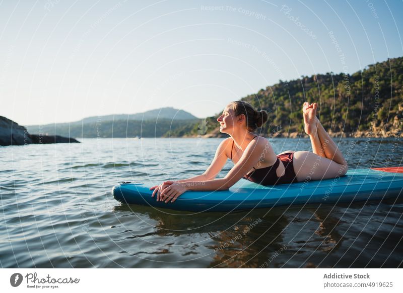 Woman lying on paddleboard in lake woman leisure hobby water rest nature wellbeing swimwear summer sup board slender shore float relax forest vacation coast