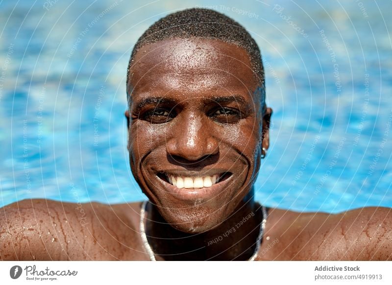 Black man in swimming pool rest recreation poolside chill pastime resort aqua shirtless fit figure calm self assured male self confident building vacation