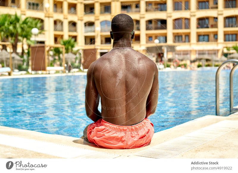 Black man in swimming pool rest recreation poolside chill pastime resort aqua shirtless fit serious figure calm self assured male self confident building