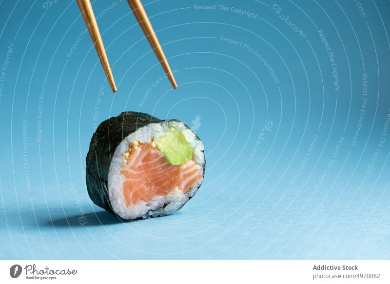 Futomaki sushi roll with chopsticks japanese futomaki asian food norwegian salmon avocado fish utensil traditional seafood ingredient light delicacy studio