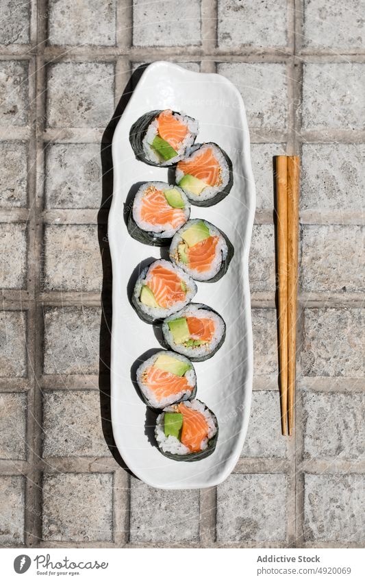 Set of Norwegian salmon futomaki rolls on street japanese sushi norwegian set fish pavement seafood street food sidewalk path walkway chopstick avocado