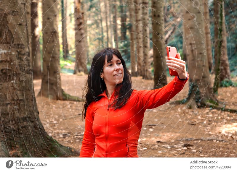 Female hiker taking selfie in forest woman smile break weekend travel smartphone female woods happy self portrait glad traveler tree nature mobile brunette