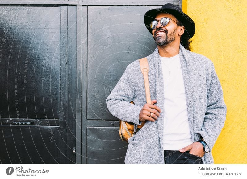 Confident trendy man near building wall street style door confident rest urban hand in pocket male adult hispanic ethnic backpack daytime personality bright