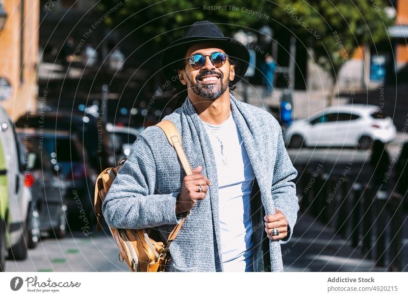 Stylish Hispanic man on city street street style urban daytime outfit rest appearance male hispanic ethnic adult modern trendy sunglasses hat sunlight