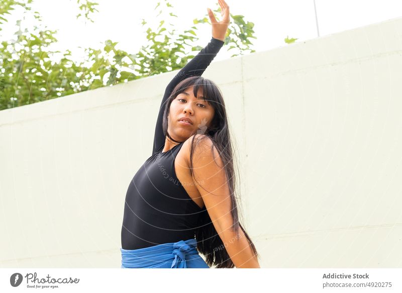 Asian female dancer with arms raised woman street wall grace building perform young ethnic asian energy style talent daytime skill practice structure urban