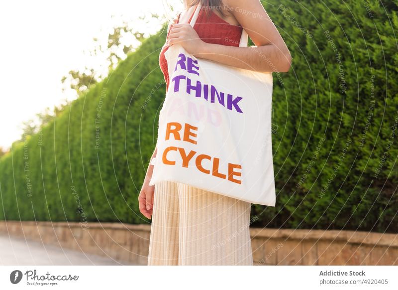 Anonymous woman with textile bag on street rethink recycle inscription eco friendly zero waste save reuse flower bush organic ecology female fabric cloth style