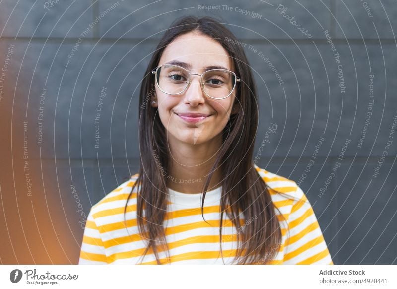 Happy young woman against gray wall smile style street happy appearance positive portrait rest female building optimist long hair dark hair casual stripe