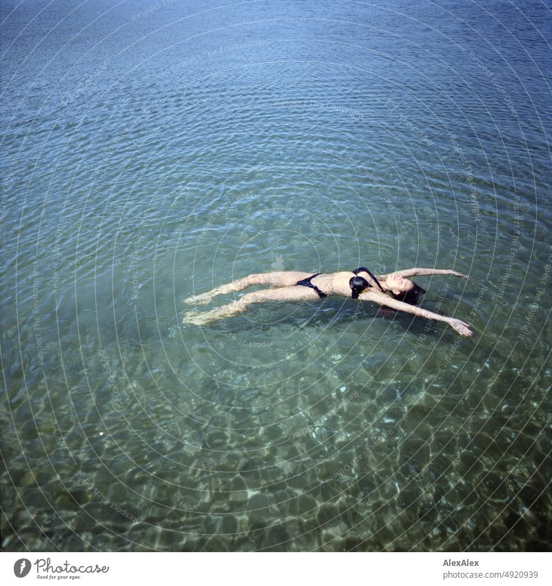 Young beautiful woman lying in the shallow water in the Baltic Sea stretching herself Lifestyle Back-light salubriously pretty Woman Athletic Slim Esthetic teen