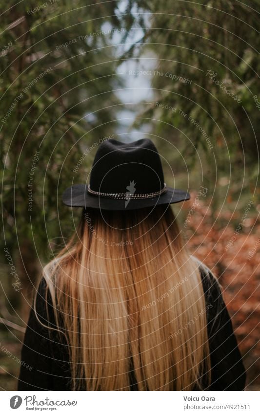 Blonde girl with a hat from behind in a green forest Woman pretty Hair and hairstyles Forest Forestry Forest path Forest walk Forest atmosphere off Hat Autumn