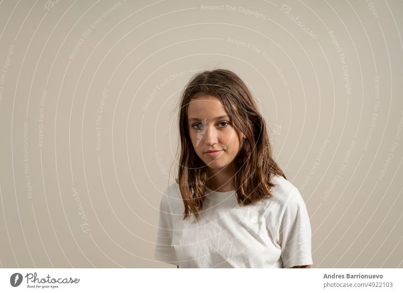 Portrait of a pretty latin teen girl with brown hair, isolated on beige studio background. youth teenager lovely look lifestyle female cute cheerful one person