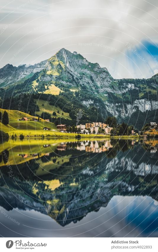 Picturesque landscape of calm lake reflecting mountains and houses nature village cottage valley picturesque highland settlement grassy scenery peaceful