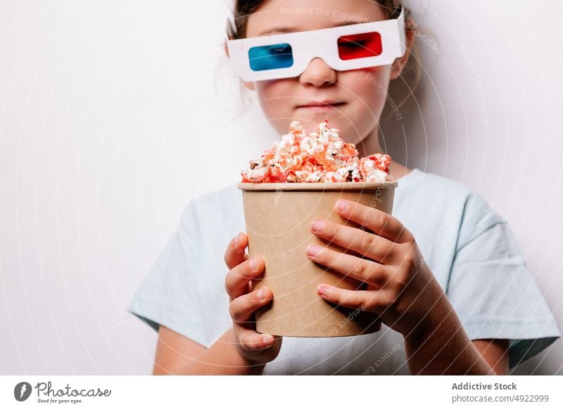 Girl in 3D glasses eating popcorn girl kid 3d amusement snack movie bucket enjoy yummy carton treat female hobby cinema food cartoon entertain happy delicious