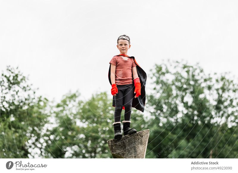 Superhero in hedgehog mask in park boy superhero play climb weekend costume pretend kneel stone block protect courage child kid cape childhood brave cloak