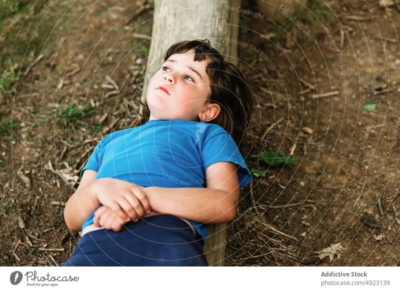 Pensive girl resting on log near bicycle park relax weekend summer calm thoughtful daytime recreation pensive lying child kid casual bike trunk tree tranquil