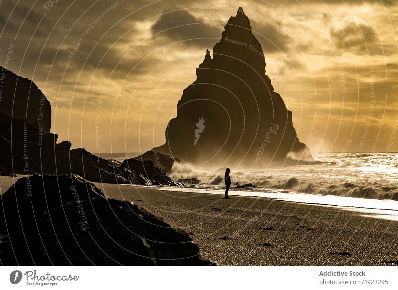 Traveler admiring volcanic black sandy beach landscape formation sea nature wave storm stone cliff silhouette admire coast ocean shore bay traveler adventure