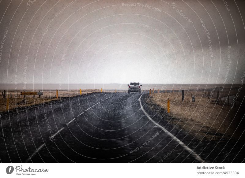 Breathtaking view of road with car near mountains under cloudy sky snow landscape journey transportation empty weather rain highland straight vehicles travel