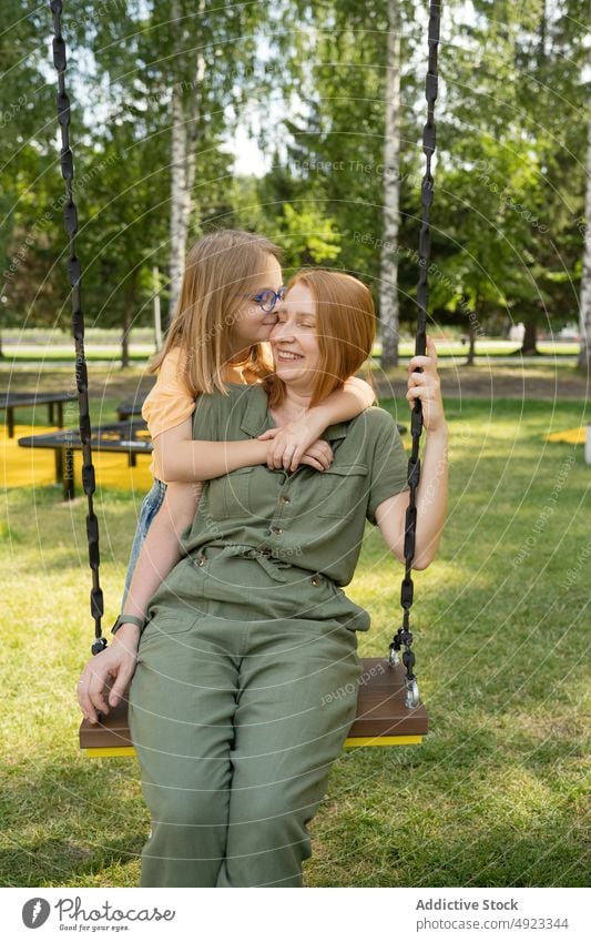 Daughter hugging mother on swing daughter park love pastime bonding motherhood spend time embrace content girl kid parent together positive summer childhood