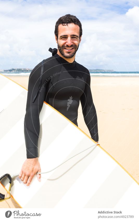 Happy young ethnic guy smiling holding surfboard on seashore man surfer beach smile shaka happy ocean athlete confident hawaiian hang loose male hispanic brunet