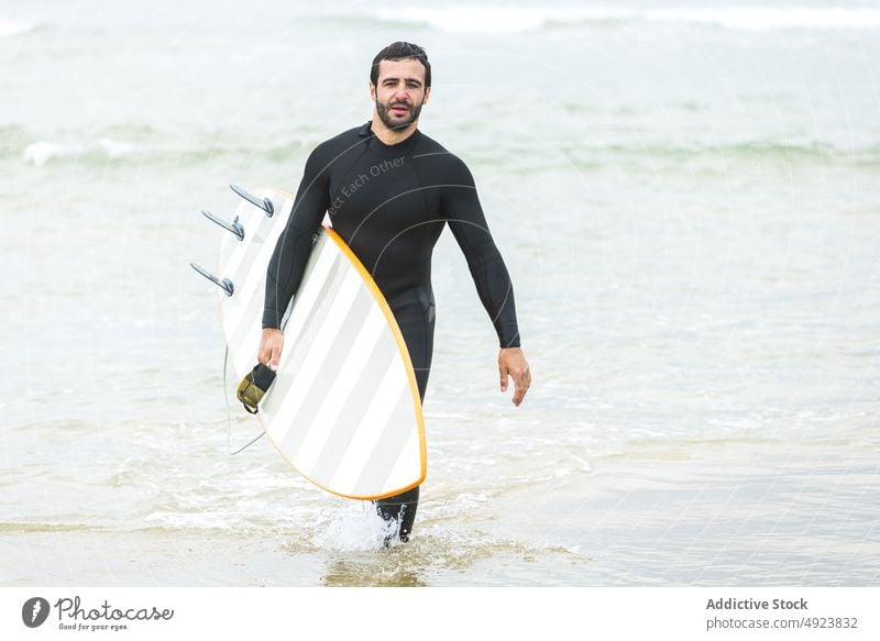 Male surfer walking in sea before riding wave man ocean surfboard sport sporty holiday enjoy healthy spend time young brunet wetsuit tourist activity surfing