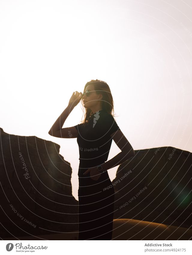 Woman standing near cliff in desert area woman nature trip travel adventure journey pastime rock sunglasses shadow tourist feminine stone enjoy light rocky