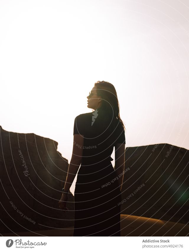 Woman standing near cliff in desert area woman nature trip travel adventure journey pastime rock sunglasses shadow tourist feminine stone enjoy light rocky