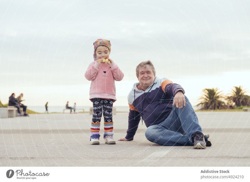 Grandfather and granddaughter on embankment grandfather rest weekend together bun eat cloudy sky man girl middle age mature spend time family glad positive