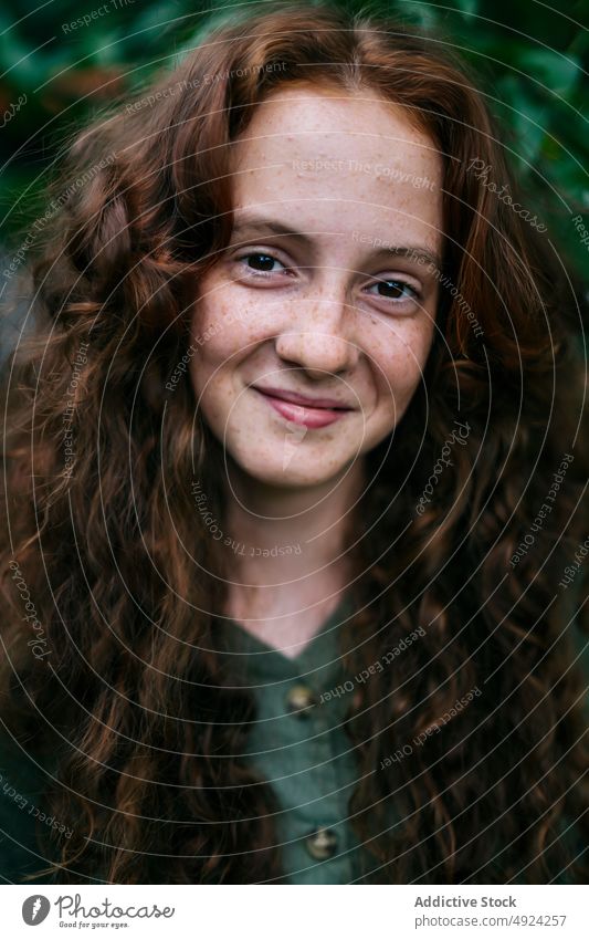 Happy redhead female smiling standing near shrub woman smile portrait positive confident red hair freckle style glad curly hair individuality content long hair