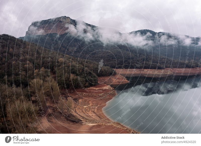 Mountains near calm river on cloudy day mountain ridge shore cover reflection water weather coast scenery gray highland range gloomy season picturesque basin