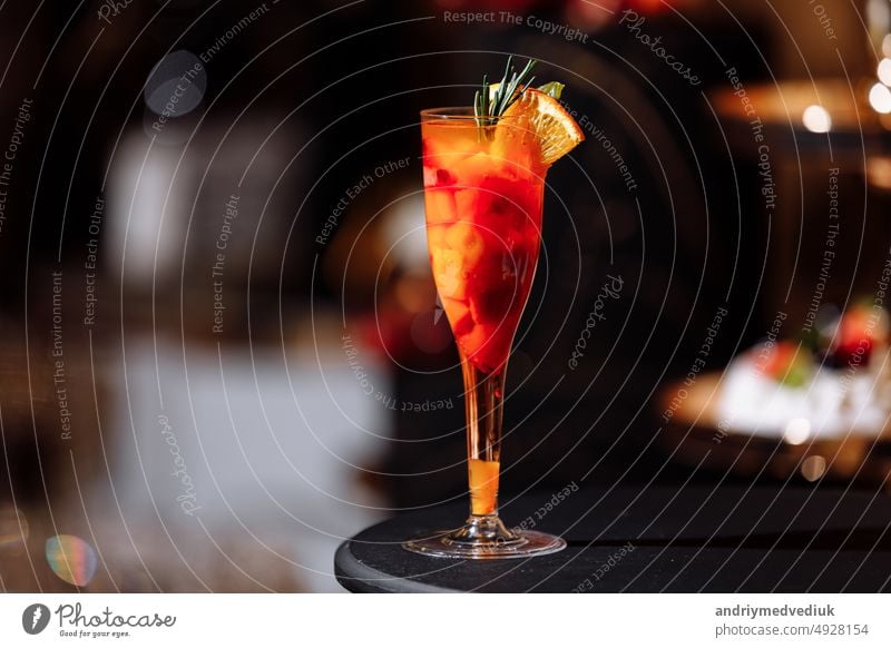 Fresh colorful exotic alcoholic cocktail with orange and rosemary on the bar desk. Tasty Soft drink with fruits. selective focus juice glass fresh food beverage